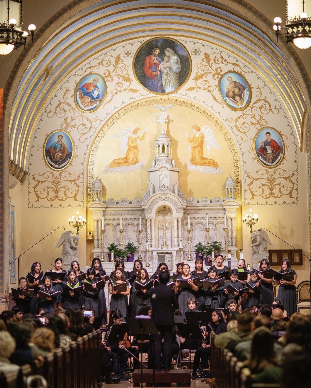 Adán Fernández conducting choir and orchestra before the altar